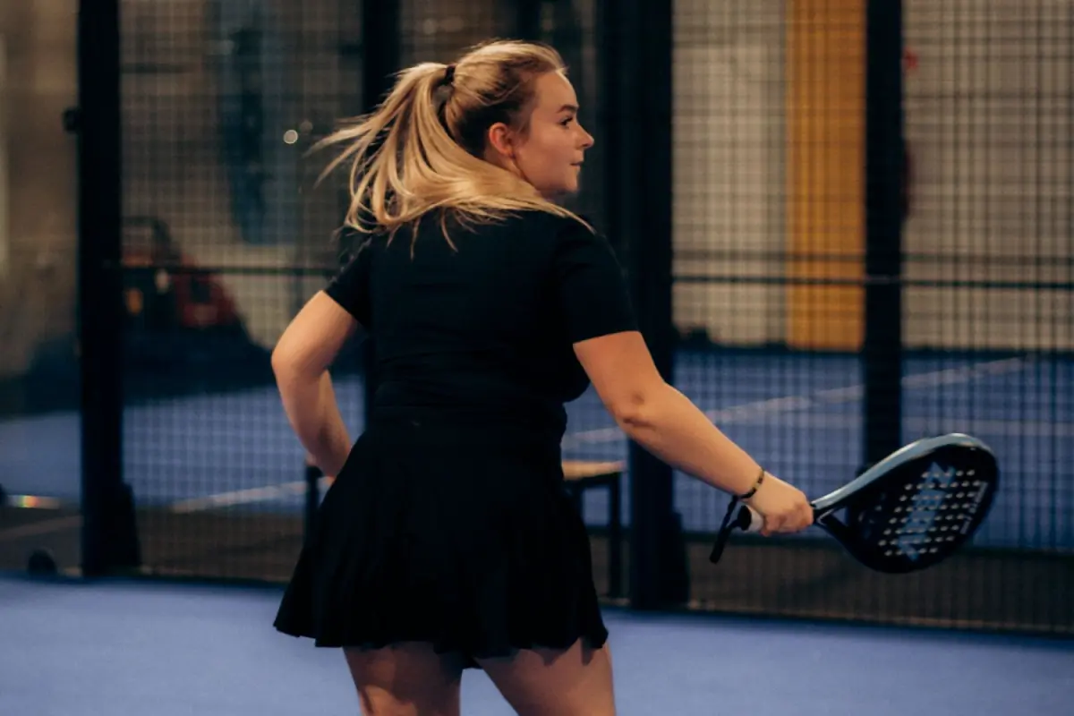 A player waiting for the ball on an indoor padel court